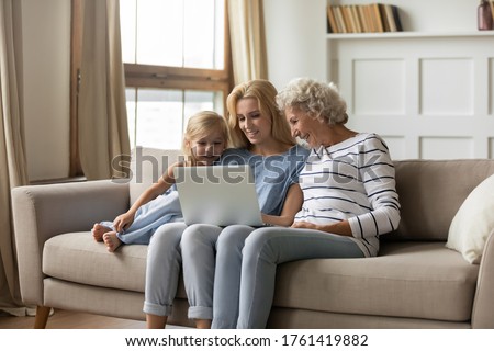 Old granny young mom little girl 3 generations women family have fun with pc, watch cartoons, use educational app for kid, choose goods, planning common vacation travel tickets hotel booking concept
