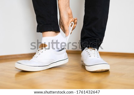 put on shoes with shoehorn on wooden floor by a man with black pants legs Royalty-Free Stock Photo #1761432647