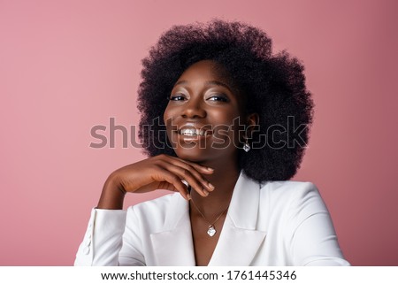 Yong beautiful happy smiling African American woman, model wearing elegant jewelry, white blazer, posing in studio, on pink background. Close up portrait. Copy, empty space for text Royalty-Free Stock Photo #1761445346