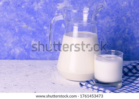 Milk in a jug on a light blue background. Copy space.