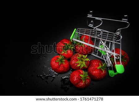 Strawberries in a supermarket cart are scattered on a black background