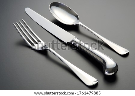 A closeup shot of stainless steel cutlery set laid on a gray surface Royalty-Free Stock Photo #1761479885