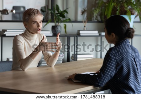 Diverse business women sit in front of each other conduct business conversation. Job interview applicant and headhunter talk. Company representative make offer to client convince buy services concept Royalty-Free Stock Photo #1761488318