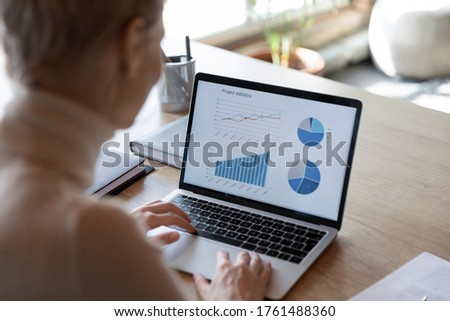 Charts, graphs, analysis sales information on laptop screen view over financier shoulder, visual representation of financial data, using helpful app for make analyze easier. Project statistics concept