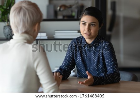 Multi ethnic indian and caucasian diverse young businesswomen sitting in front of each other in office during business meeting. HR manager and vacancy candidate talk, job interview and hiring concept Royalty-Free Stock Photo #1761488405