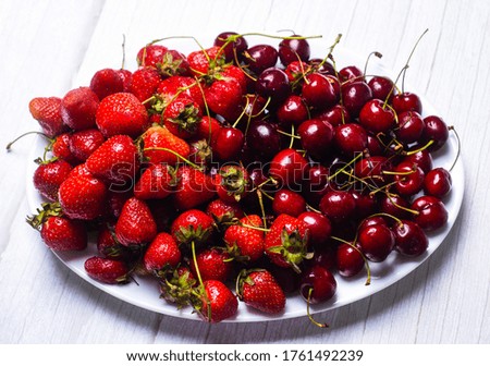 Ripe cherries and strawberries on a white dish