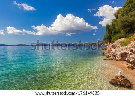 View to pebbles through transparent water at Ionian sea floor under bright sunlight near Ipsos, Corfu, Greece