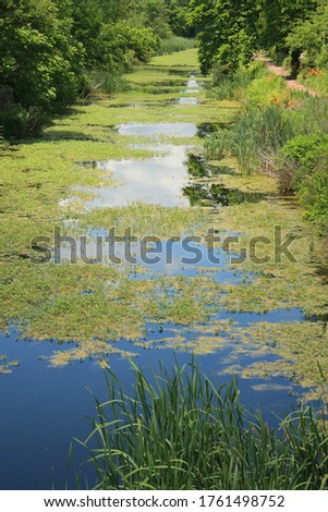 canal of water with blue sky and clouds reflecting in the water. Vertical format photography. 