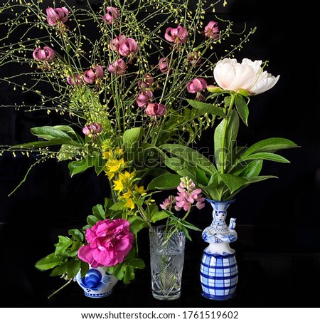 Four bouquets of summer garden flowers in different vases. Rose hip, peony, lupine, tiny lilies with black background. Image with selective focus, noise effect and toning