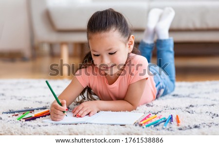 Adorable Kid Girl Drawing Picture Using Colorful Pencils Lying On Floor At Home. Child's Hobby Concept