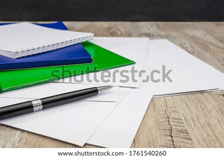Black pen, colored folders for documents, envelopes, notebooks, stationery on the table.