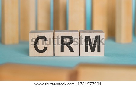 CRM Customer Relationship Marketing written on a wooden cubeon a blue table with wooden background.. Business concept
