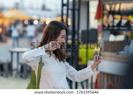 Young Asian traveler woman taking a selfie in the night market, Bangkok, Thailand.