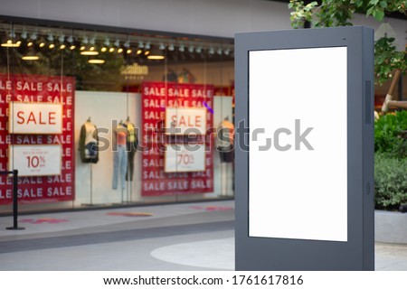 Blank white screen city sale advertisement billboard lightbox mockup. Street poster advertisement light board mock up with blurred female fashion store background.