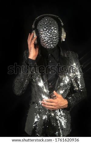 Mr discoball with obscured face and headphones in nightclub dancing against a black background