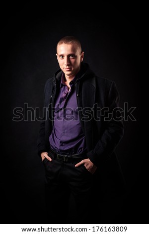 Cool businessman standing on dark gradient background. Picture of a young casual man, over black background.