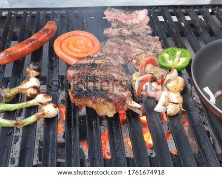 Cowboy steak with sausage and vegetables over grill