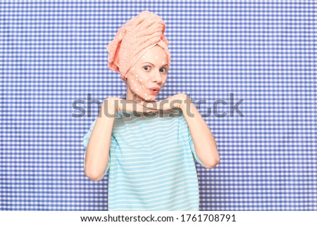 Portrait of cute amazed impressed girl with anti-acne skincare product on face, with towel on her head, standing over shower curtain background. Care for acne-prone skin, hair care. Beauty concept