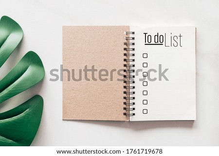 Notebook with to do list words on white marble texture background.