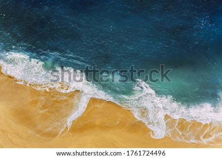 Sea coast, view from the height. Yellow sandy beach with blue sea. A deserted beach with a bird's-eye view. Sea waves roll on the sandy beach. Beautiful sea landscape. Ocean, waves, sand. Copy space