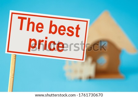 A sign for the sale of real estate and a house in the background. Real estate sale concept