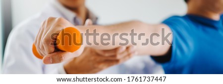 Physiotherapist man giving exercise with dumbbell treatment About Arm and Shoulder of athlete male patient Physical therapy concept Royalty-Free Stock Photo #1761737447