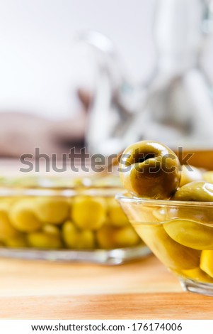 green olives on wooden table , focus on foreground