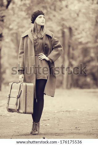 Redhead girl with suitcase at autumn outdoor. Photo in old color image style.