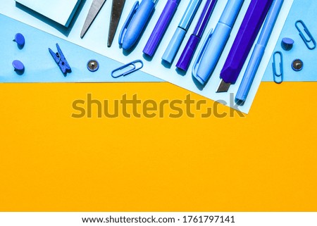 Overhead shot of school supplies, Blue stationary on yellow background, copy space for text, scissors, pencil, pen clothespin and paper clips, back to school