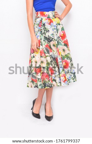 Young in blue shirt with floral ,palm pattern  skirt with high hill shoes posing on white background

