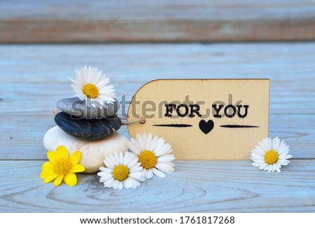A closeup of the stones with Daisy flowers and romantic love card isolated on the wooden surface