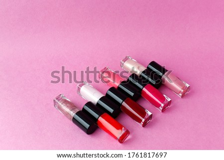 Red, pink, white nail polish lies on a pink background. Means for manicure.
