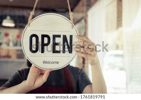 Reopen. barista or waitress woman turning open sign board on glass door in modern cafe coffee shop ready to service, cafe restaurant, retail store, small business owner, food and drink concept