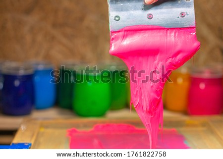 pink color dripping from hand screen printing during printing tee shirt 
in tee shirt factory.
