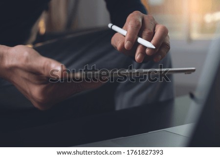 Casual business man with stylus pen using digital tablet surfing the internet, online working on laptop computer in office. Freelance working project, closeup. Startup business, technology concept