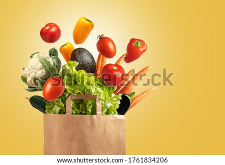 Eco friendly reusable shopping bag filled with vegetables on a yellow background, copy space