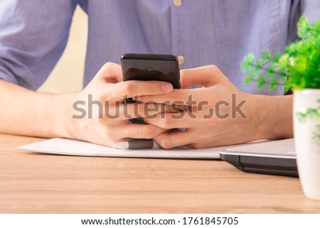 close-up of hands with mobile phone at desk