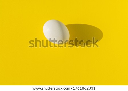 White boiled egg photographed with a hard shadow on a yellow background. Template for a pattern.