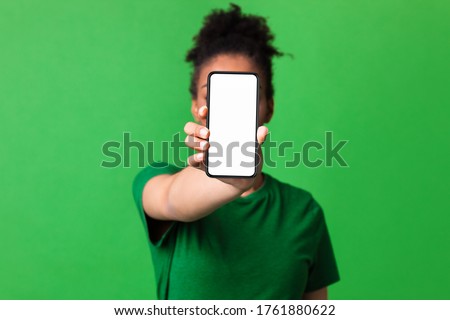 Mobile App Advertising. African woman showing blank cellphone screen, mockup, selective focus, green studio wall