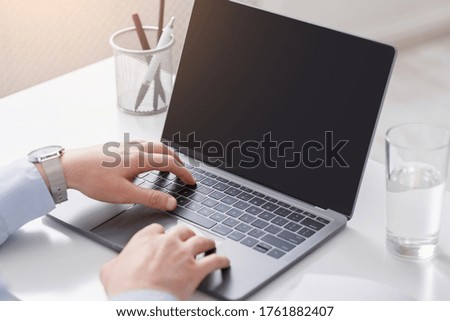Work with modern technology remotely from home or workplace. Man hands are typing on laptop with blank screen, sun flare
