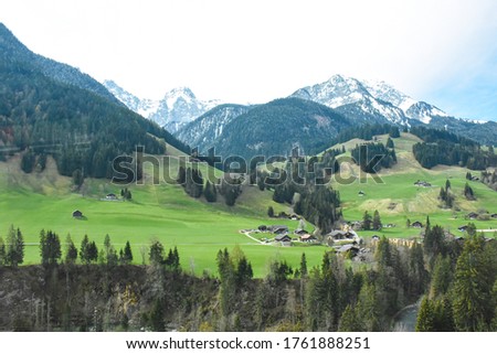 Colorful picture of Swiss village on green grass area with Alps moutain under blue sky, from Golden pass line,  Zweisimmen to Montreux, Switzerland: 7/5/2562