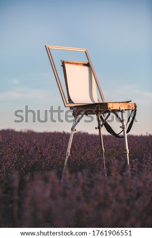An easel and a white canvas in a lavender field. The concept of creativity and inspiration. Space for text. Mock up