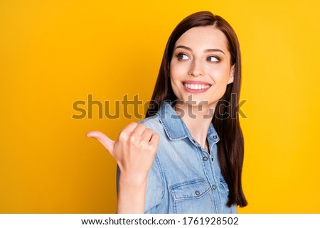 Portrait of positive cheerful girl promoter indicate sales point thumb finger copyspace recommend suggest select adverts promo wear denim jeans outfit isolated over shine color background