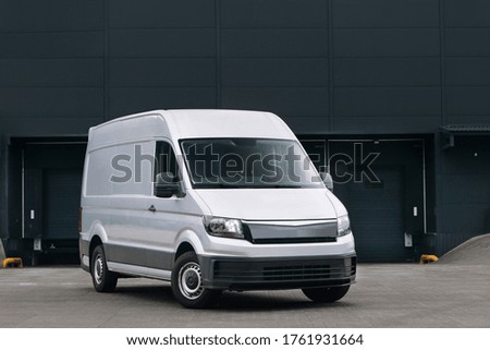 Delivery van near a warehouse at logistic park. Modern minivan ready for loading. Cargo and storage HUB near the city. Lorry truck at the industrial entrepot. Courier and express delivery service  Royalty-Free Stock Photo #1761931664