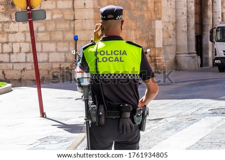 Back view of Spanish municipal police  with "Policia Local" logo emblem on uniform maintain public order in the streets of Jaen, Spain