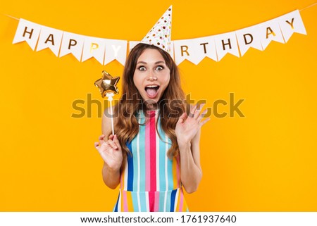 Image of excited cute woman in party cone posing with magic wand isolated over yellow background