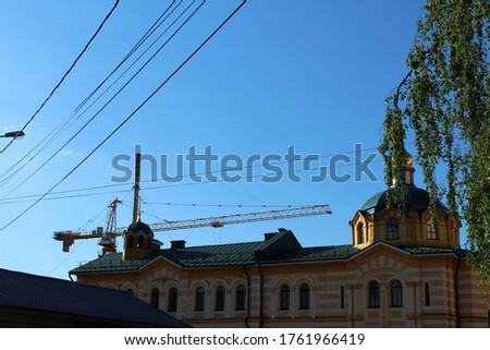 construction crane on a background of blue sky and church