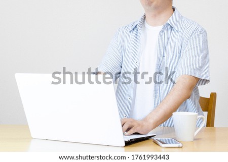 A man working at home with a laptop in plain clothes. Image of working from home and side business
