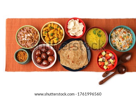 Indian whole meal with yellow dal, vegetable pulao, chapati,gulab jamun, salad, papad, pickle, chana masala curry and aloo gobi Royalty-Free Stock Photo #1761996560