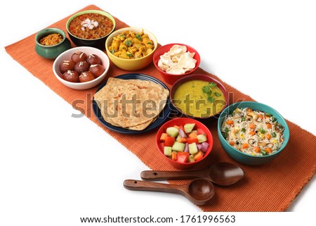 Indian whole meal with yellow dal, vegetable pulao, chapati,gulab jamun, salad, papad, pickle, chana masala curry and aloo gobi Royalty-Free Stock Photo #1761996563